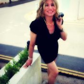 Caprice is wearing a mini length black dress. Translife Dressing Service Model Caprice